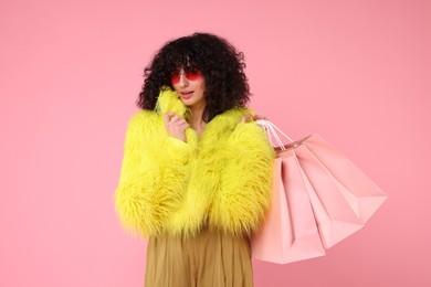 Photo of Happy young woman with shopping bags on pink background