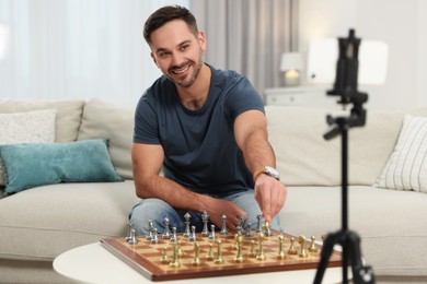 Photo of Teacher near chessboard conducting online lesson at home. Time for hobby