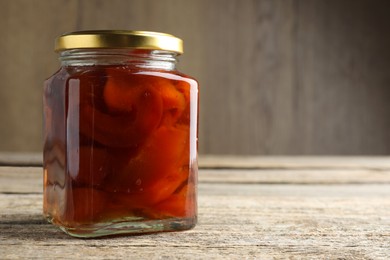 Photo of Tasty homemade quince jam in jar on wooden table, closeup. Space for text