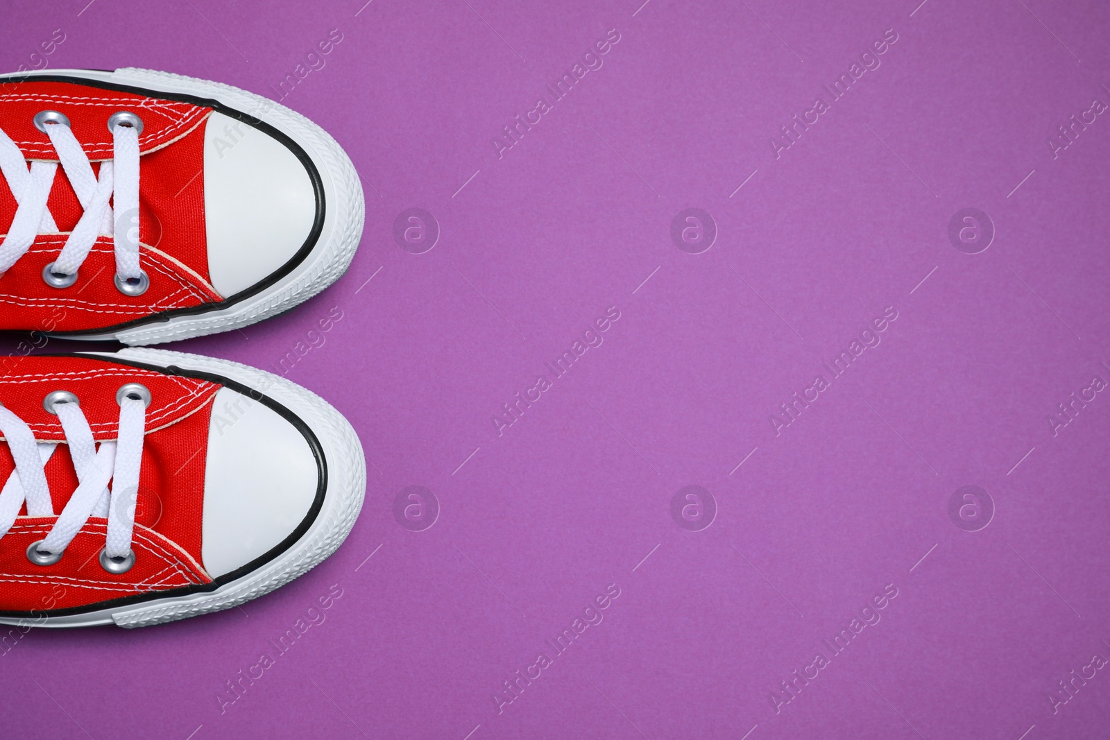 Photo of Pair of new stylish red sneakers on purple background, flat lay. Space for text
