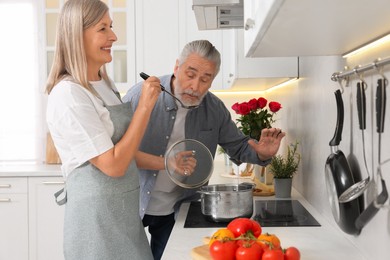 Affectionate senior couple cooking together in kitchen
