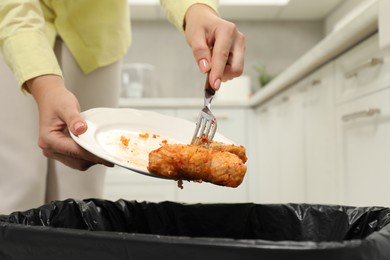 Woman throwing cabbage rolls into bin indoors, closeup