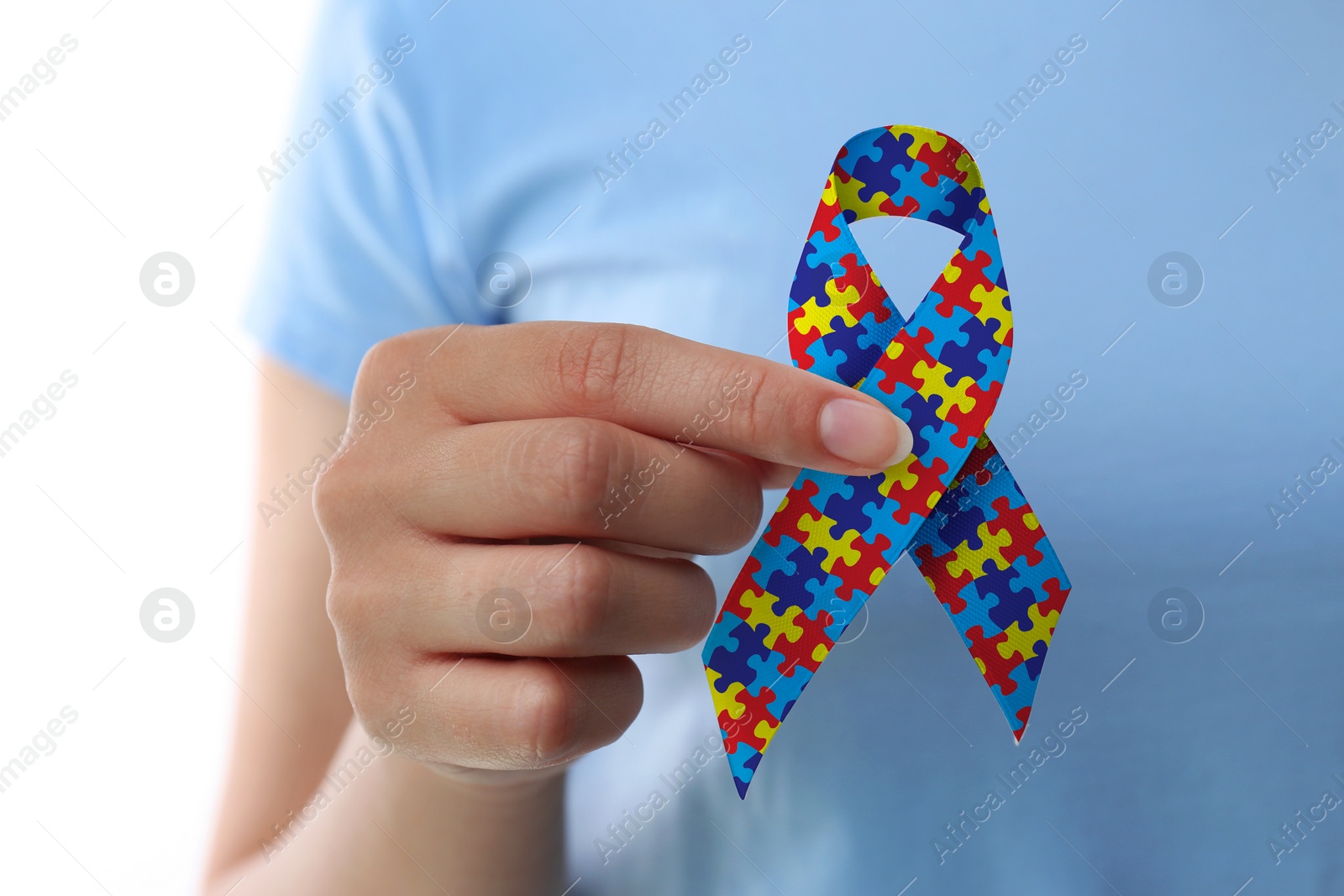 Image of World Autism Awareness Day. Woman with colorful puzzle ribbon on white background, closeup