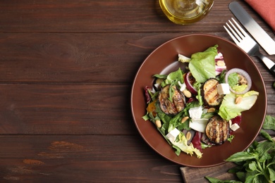 Photo of Delicious salad with roasted eggplant, feta cheese and arugula served on wooden table, flat lay. Space for text