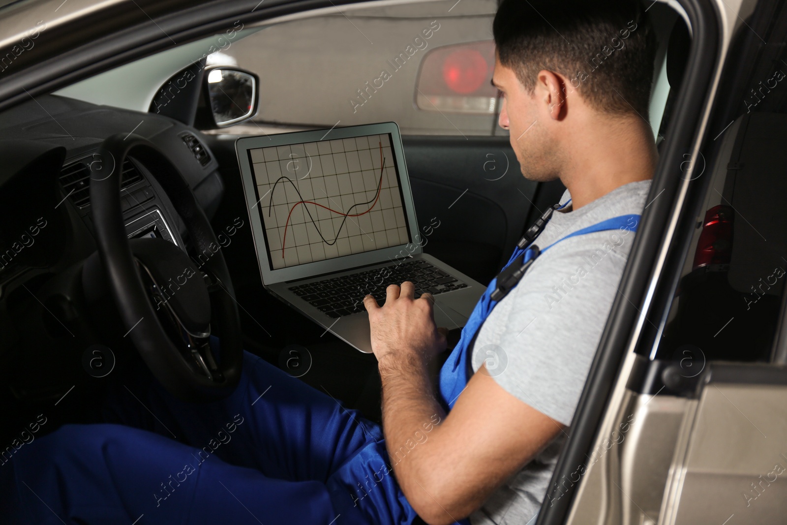 Photo of Mechanic with laptop doing car diagnostic at automobile repair shop