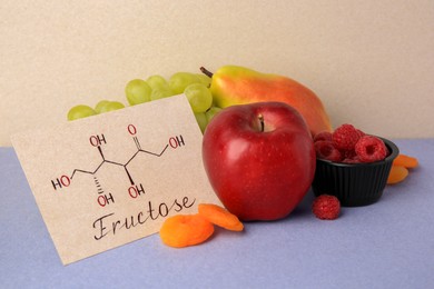 Card with word Fructose, delicious ripe fruits, raspberries and dried apricots on color background