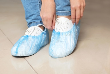 Woman putting on blue shoe covers, closeup