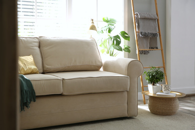 Stylish beige sofa in modern living room interior