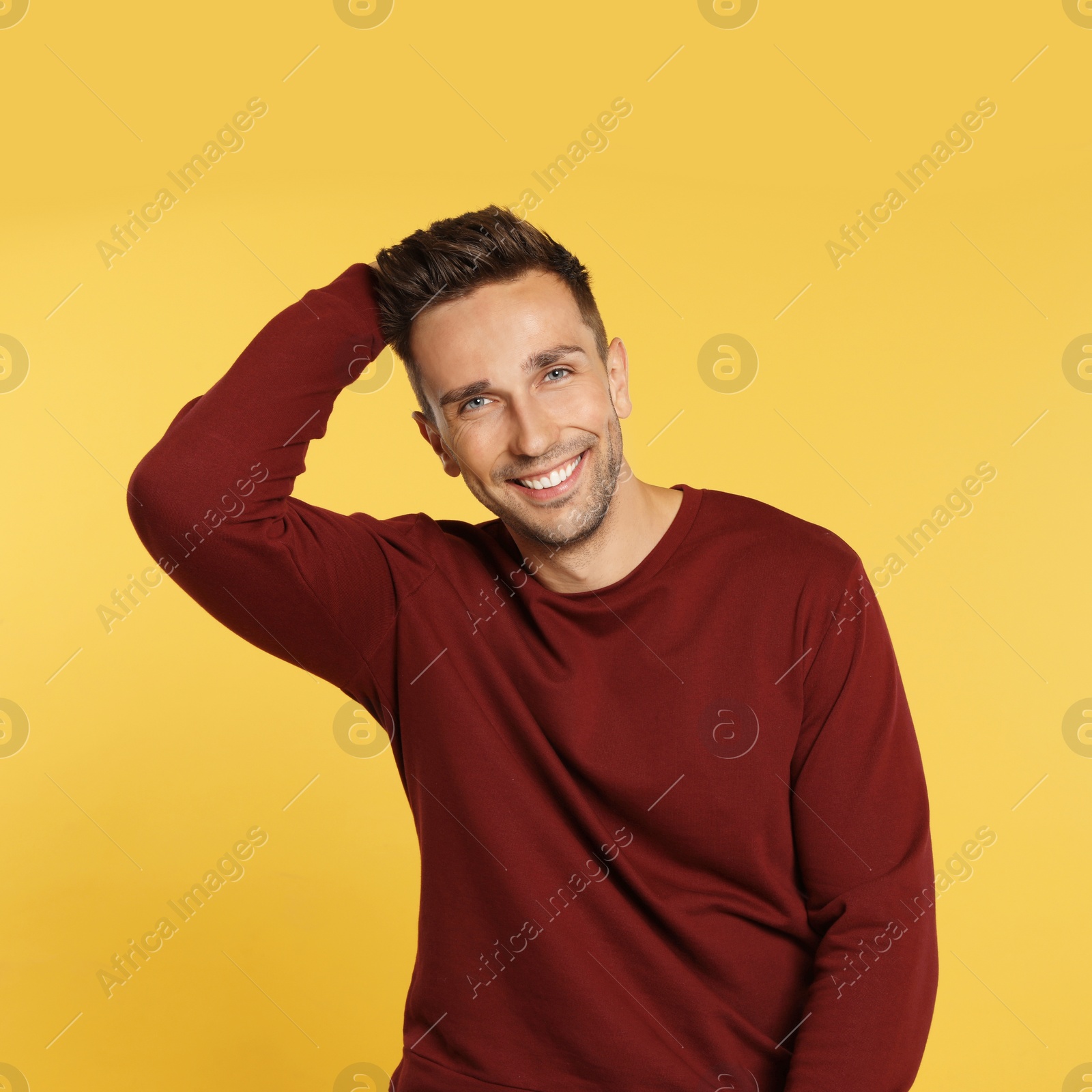 Photo of Happy young man in sweatshirt on yellow background. Winter season