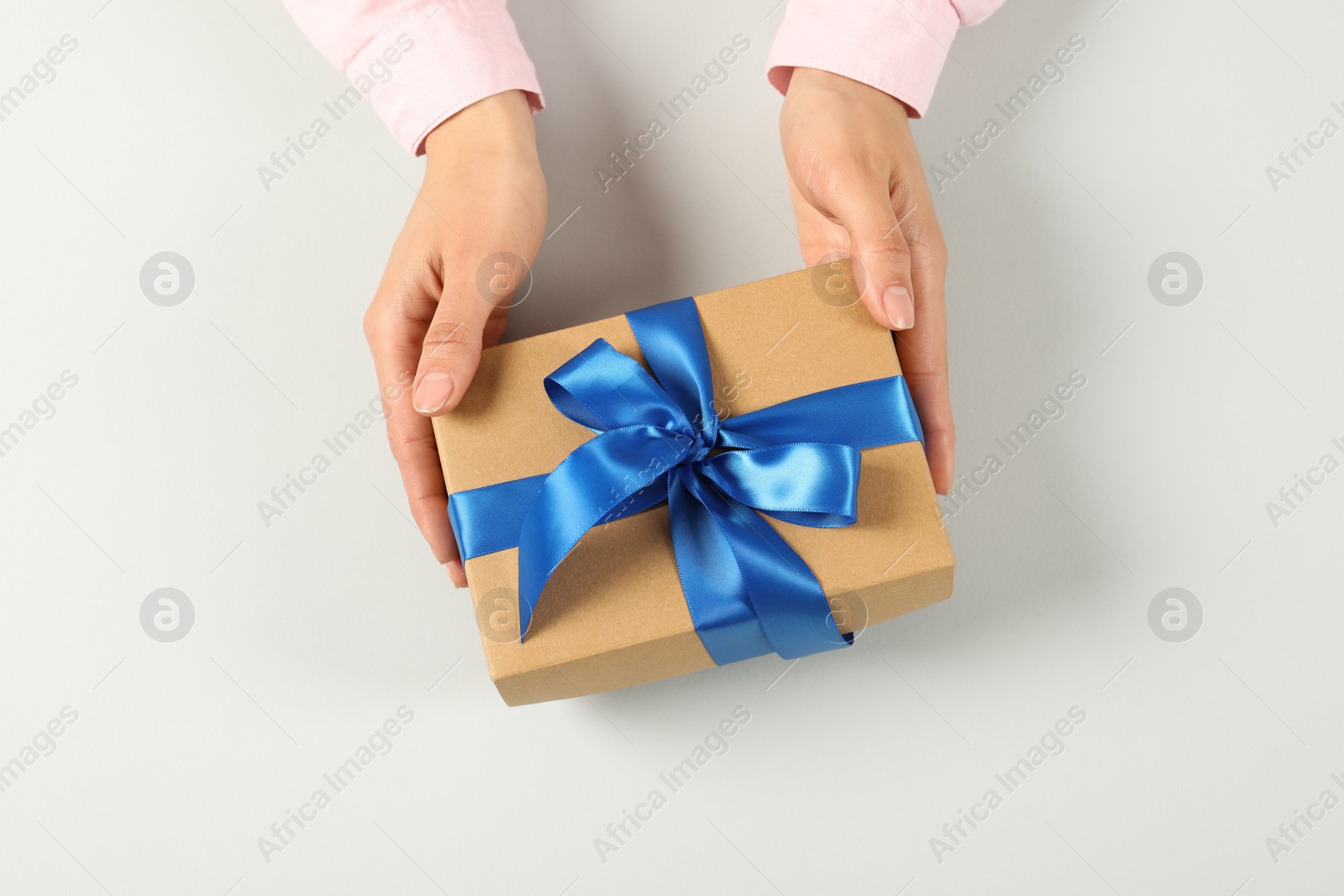 Photo of Woman holding gift box on light background, top view