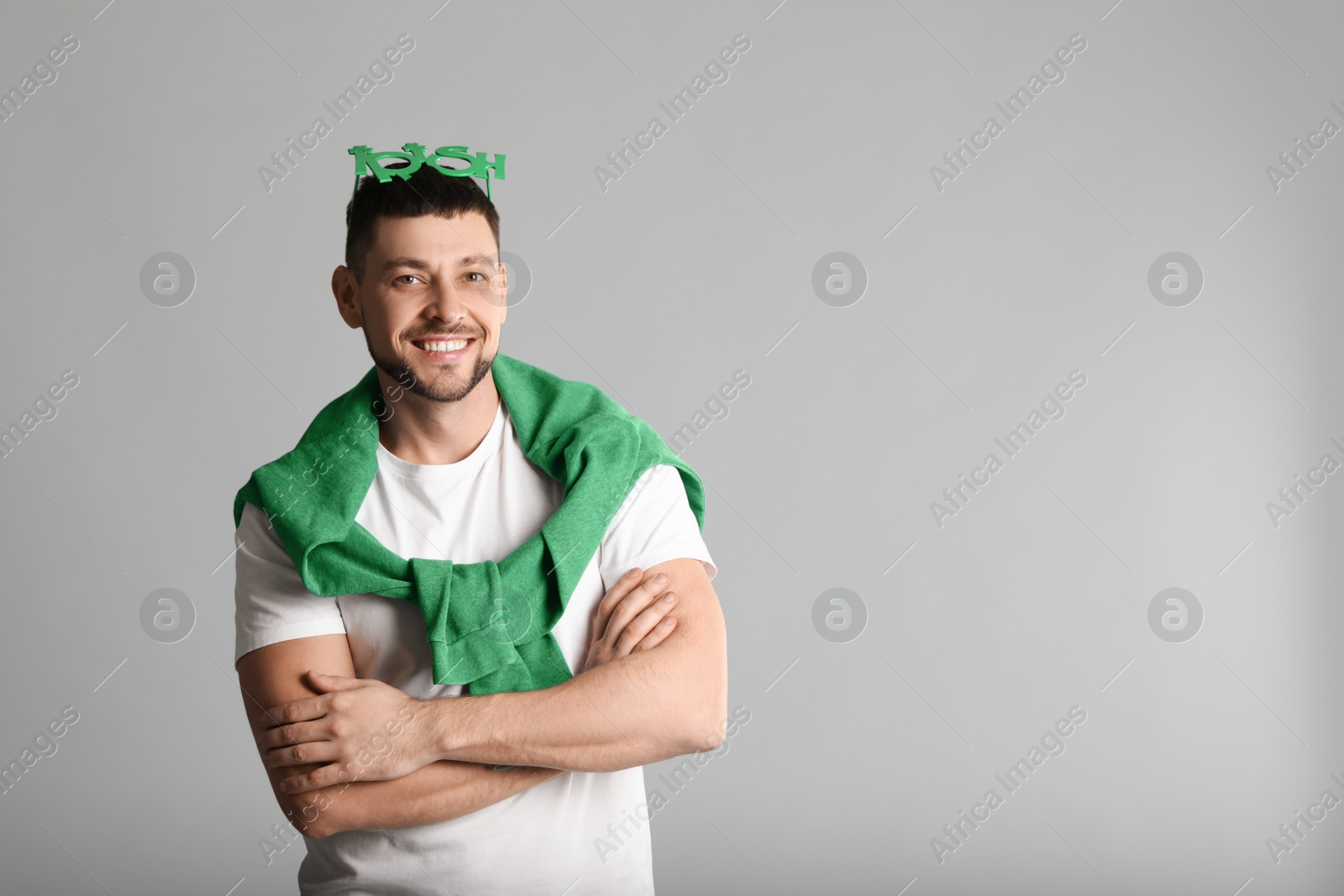 Photo of Happy man in St Patrick's Day outfit on light grey background, space for text