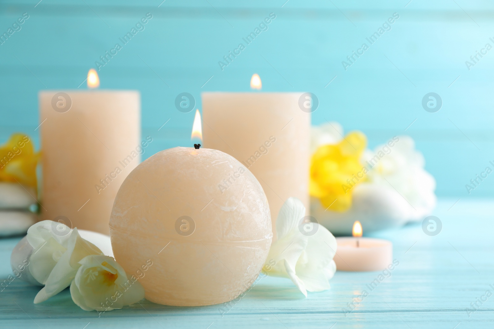 Photo of Burning candles, spa stones and flowers on table. Space for text