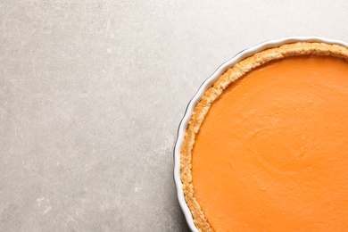 Photo of Fresh delicious homemade pumpkin pie on gray background, top view with space for text