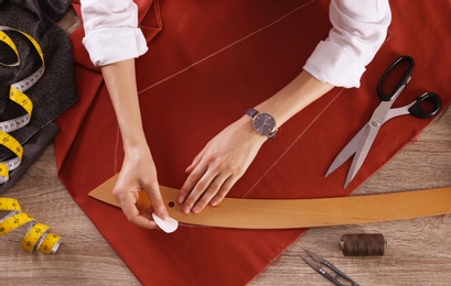 Photo of Tailor working with cloth at table in atelier, top view