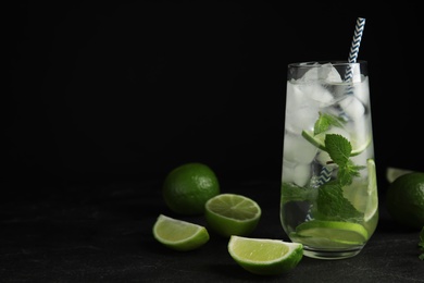 Photo of Delicious mojito and ingredients on black table. Space for text