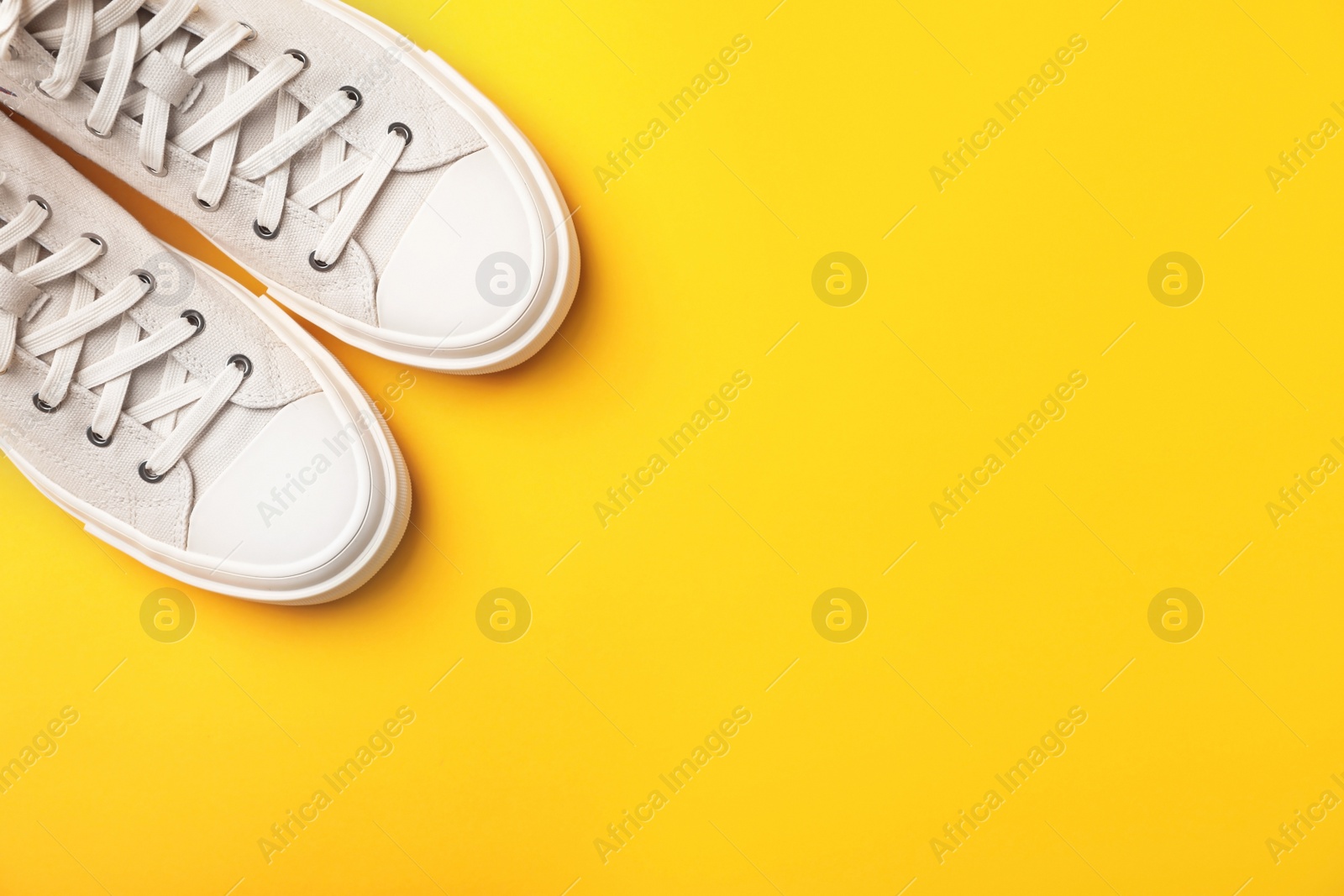 Photo of Pair of white sneakers on color background, top view