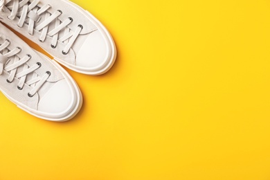 Photo of Pair of white sneakers on color background, top view