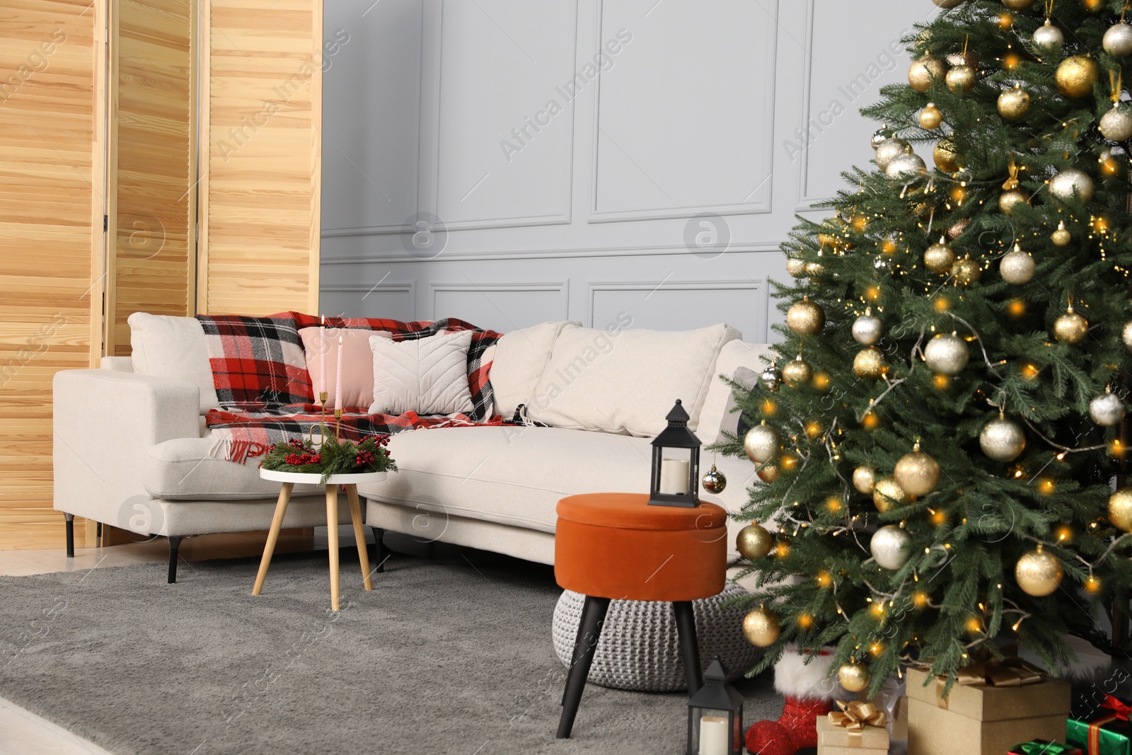 Photo of Beautiful Christmas tree, gift boxes and sofa in living room