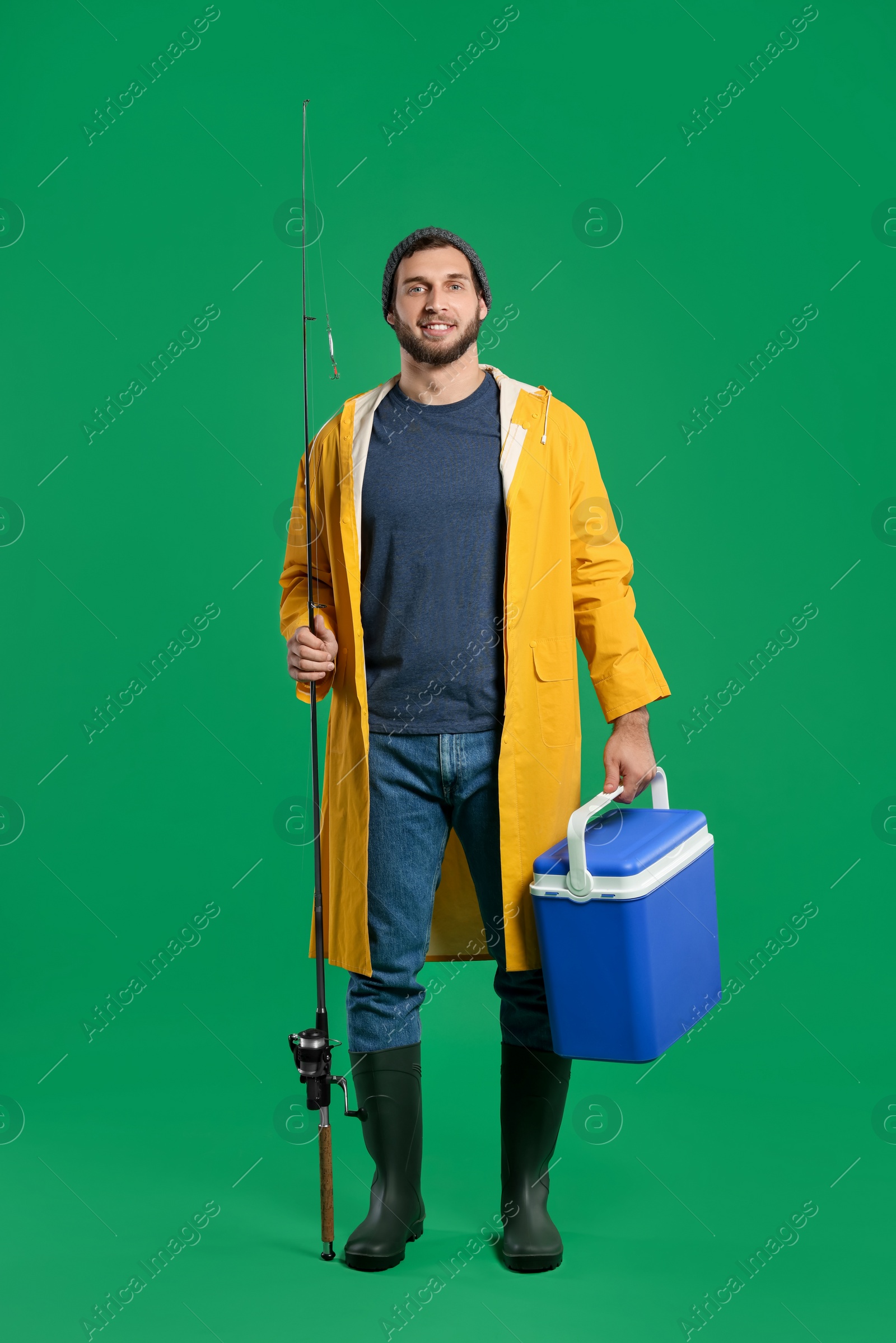 Photo of Fisherman with fishing rod and cool box on green background