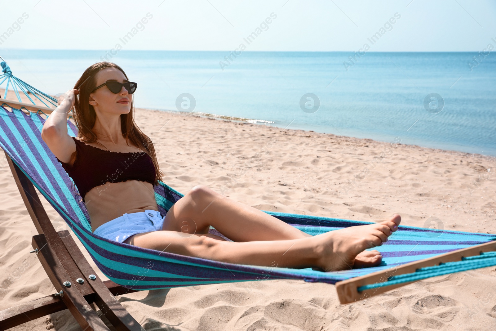 Photo of Young woman relaxing in hammock on beach