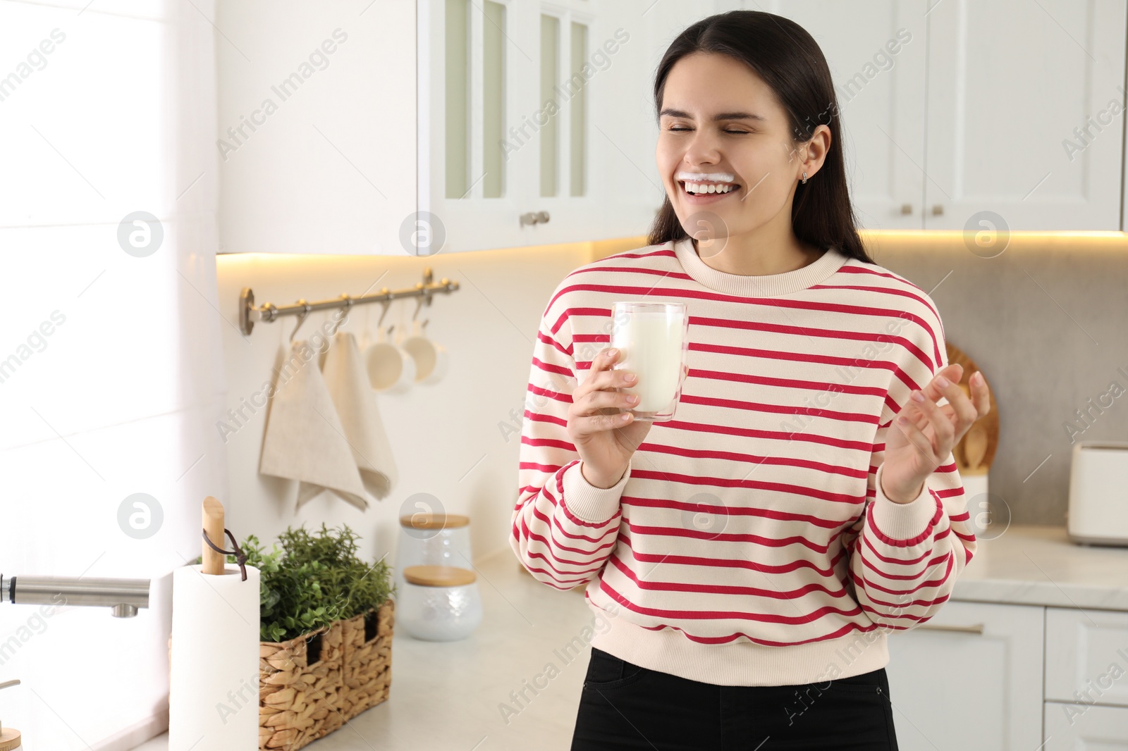 Photo of Happy woman with milk mustache holding glass of tasty dairy drink in kitchen. Space for text