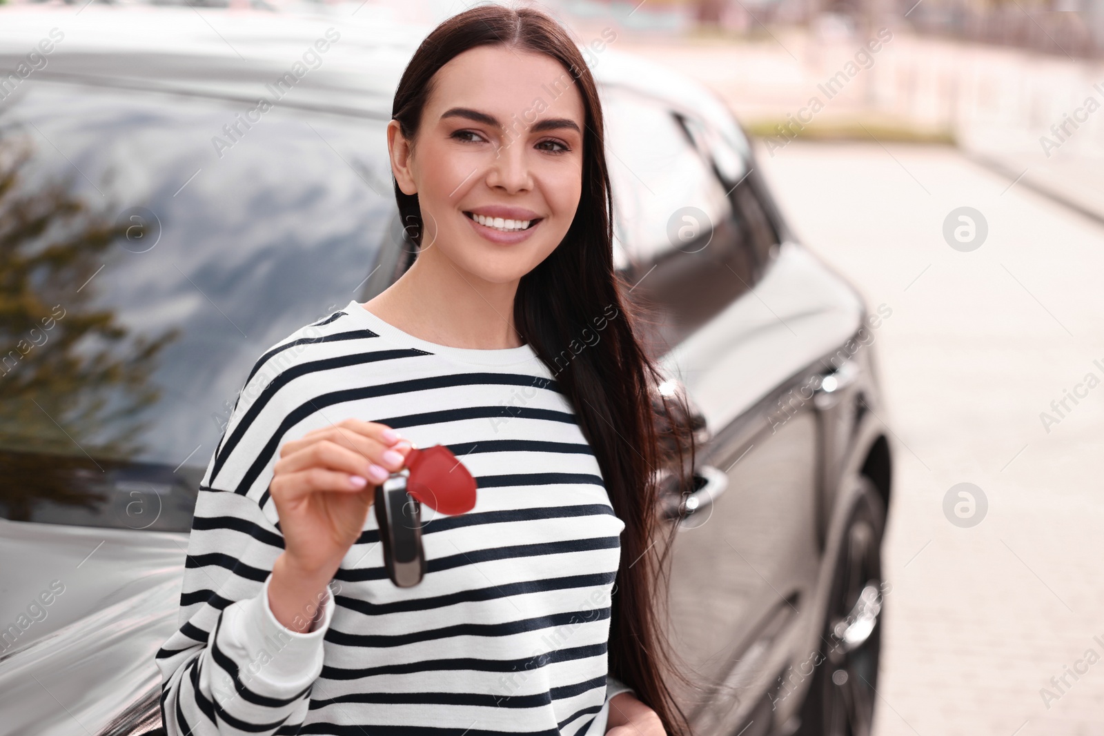 Photo of Woman holding car flip key near her vehicle outdoors