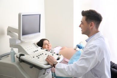 Photo of Young pregnant woman undergoing ultrasound scan in clinic