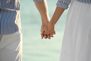 Photo of Happy young couple holding hands on beach, closeup