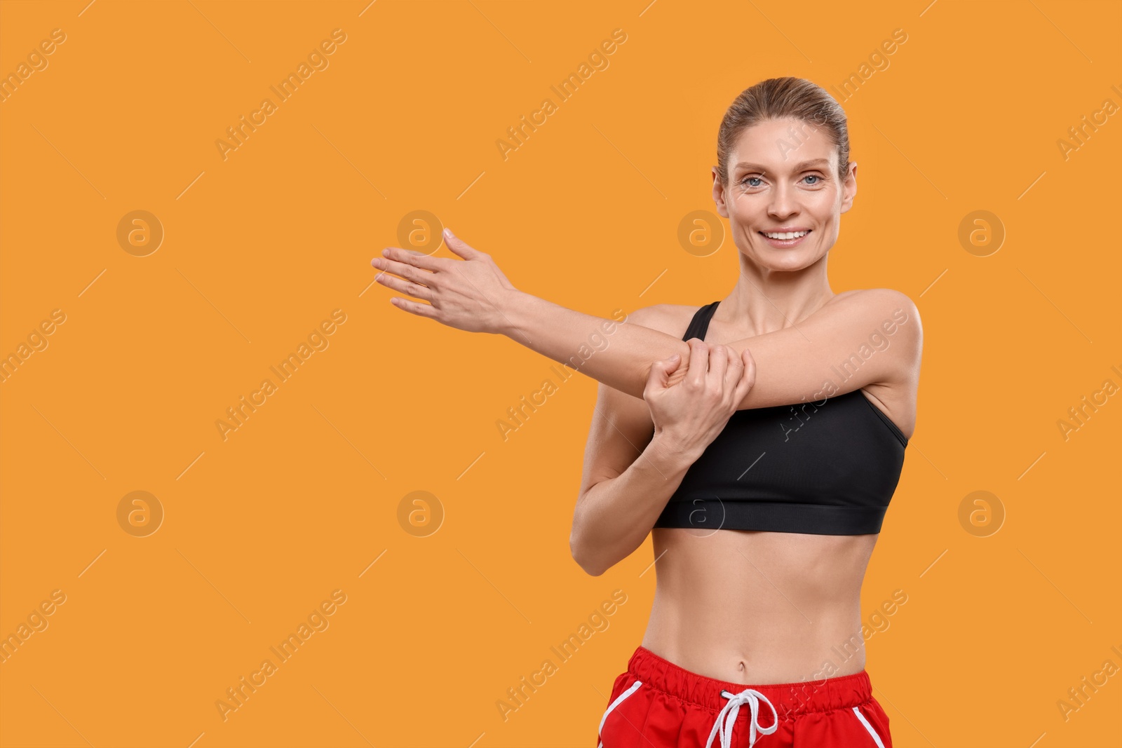 Photo of Portrait of sportswoman stretching on yellow background, space for text