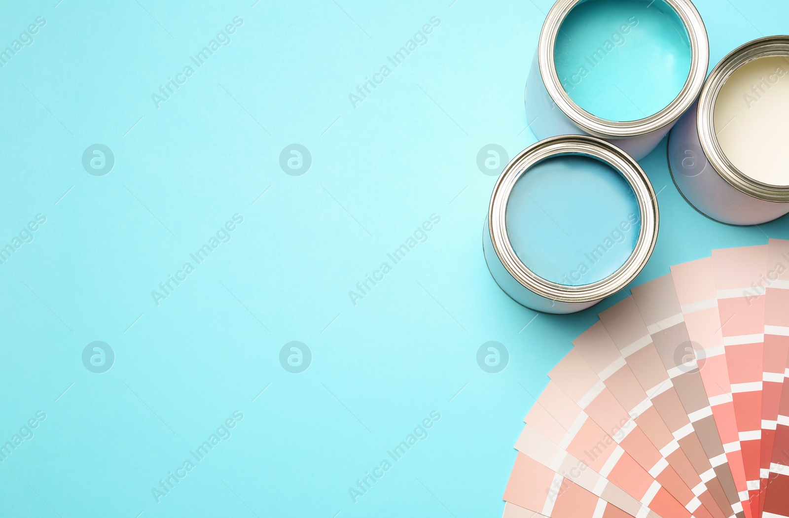 Photo of Paint cans and color palette on blue background, top view. Space for text