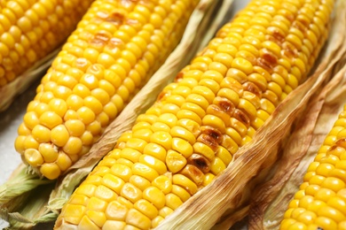 Photo of Delicious grilled sweet corn cobs on table, closeup