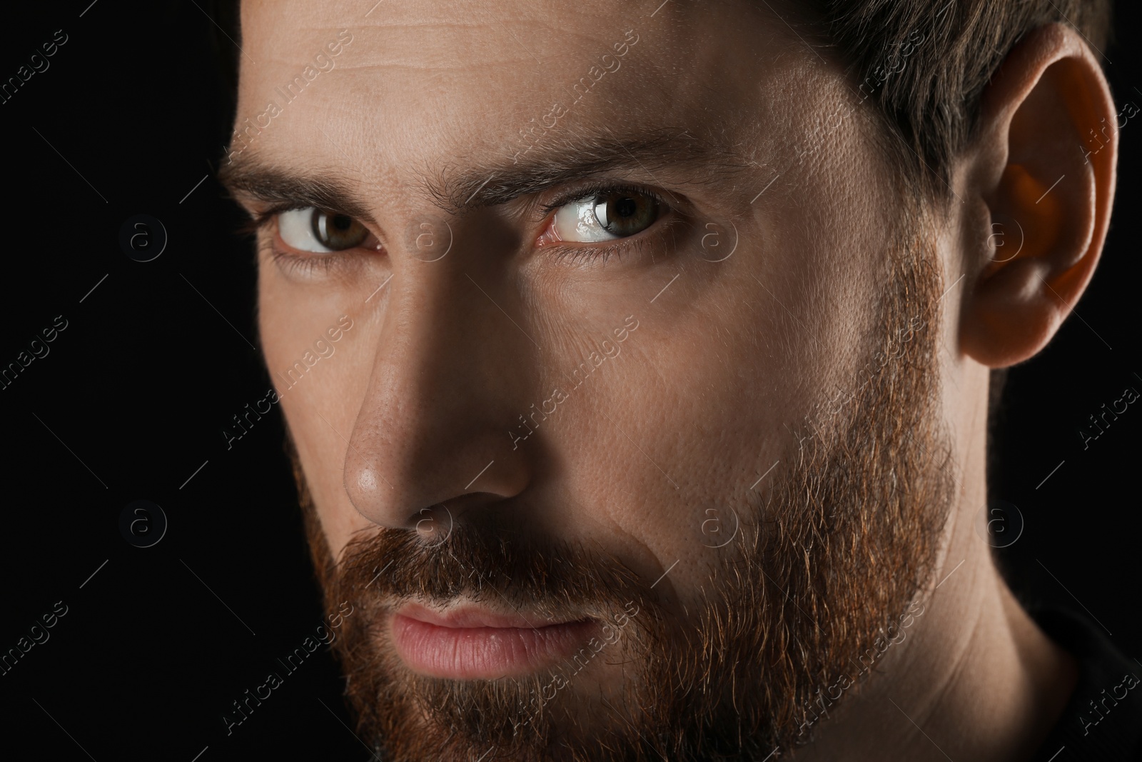 Photo of Evil eye. Man with scary eyes on black background, closeup