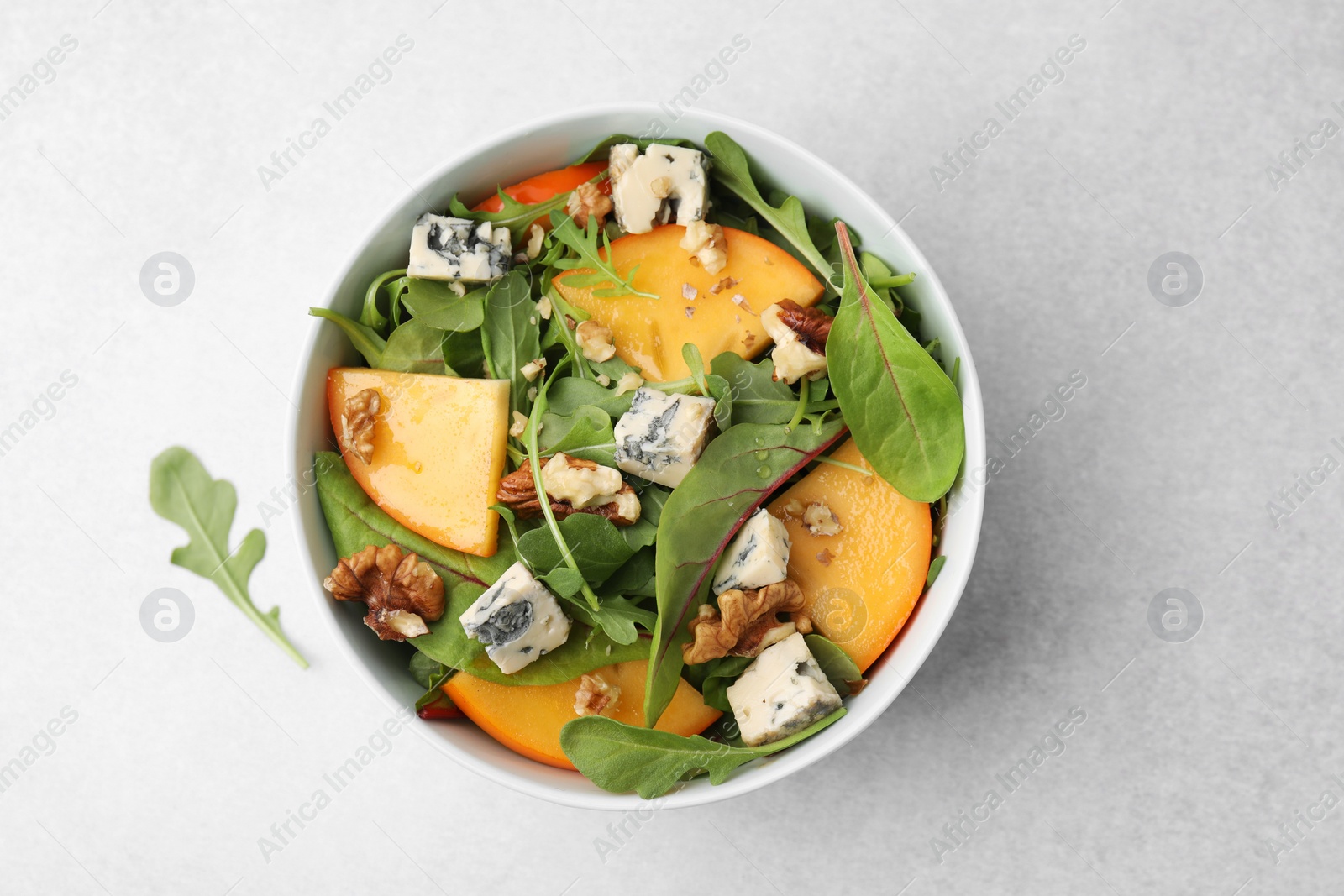 Photo of Tasty salad with persimmon, blue cheese and walnuts served on white table, top view