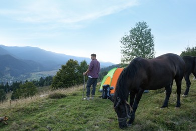 Photo of Tourist and horse near camping tent in mountains