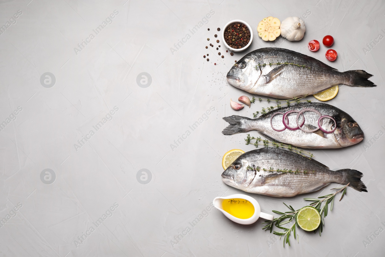 Photo of Flat lay composition with fresh raw dorado fish and ingredients on light grey table, space for text