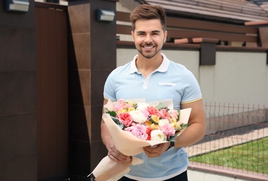 Photo of Young handsome man with beautiful flower bouquet outdoors