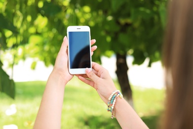 Woman using smartphone with blank screen outdoors, closeup. Mock up for design