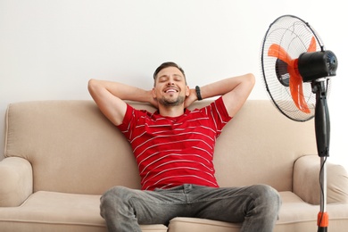 Photo of Man refreshing from heat in front of fan at home