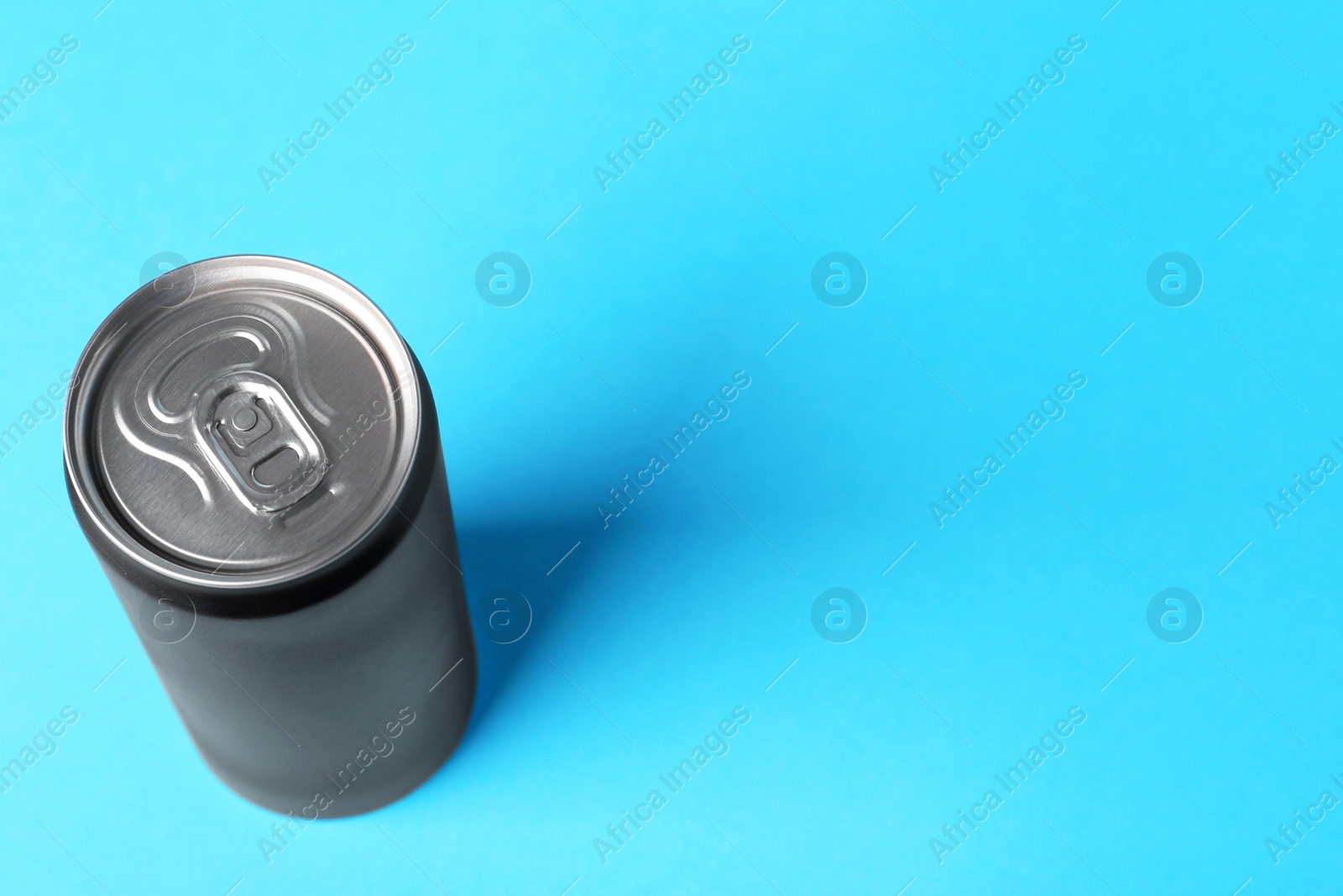 Photo of Energy drink in black can on light blue background, above view. Space for text