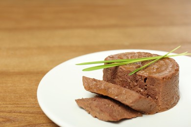 Photo of Plate with pate and grass on wooden table, closeup. Pet food