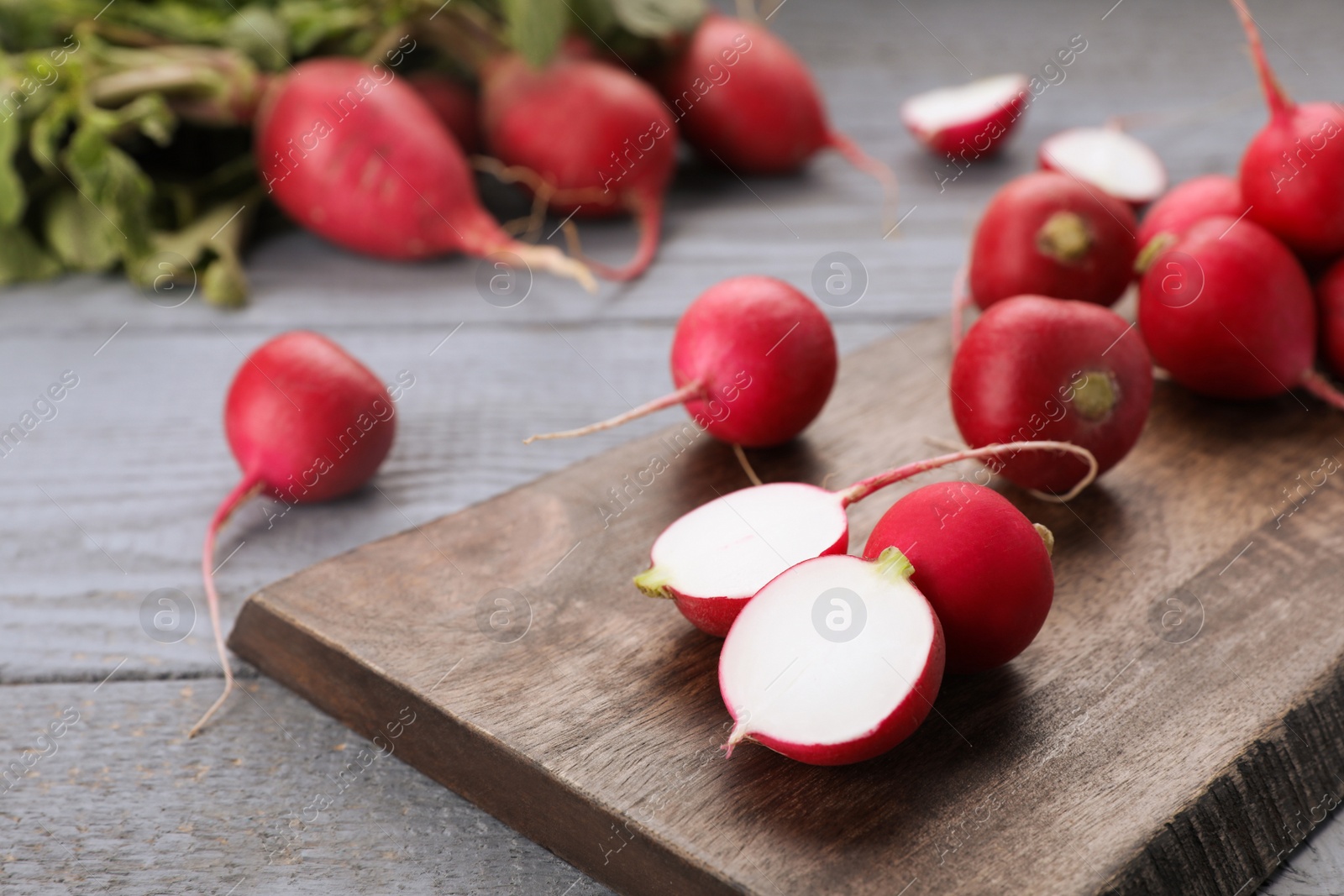 Photo of Fresh ripe radishes on grey wooden table, closeup. Space for text