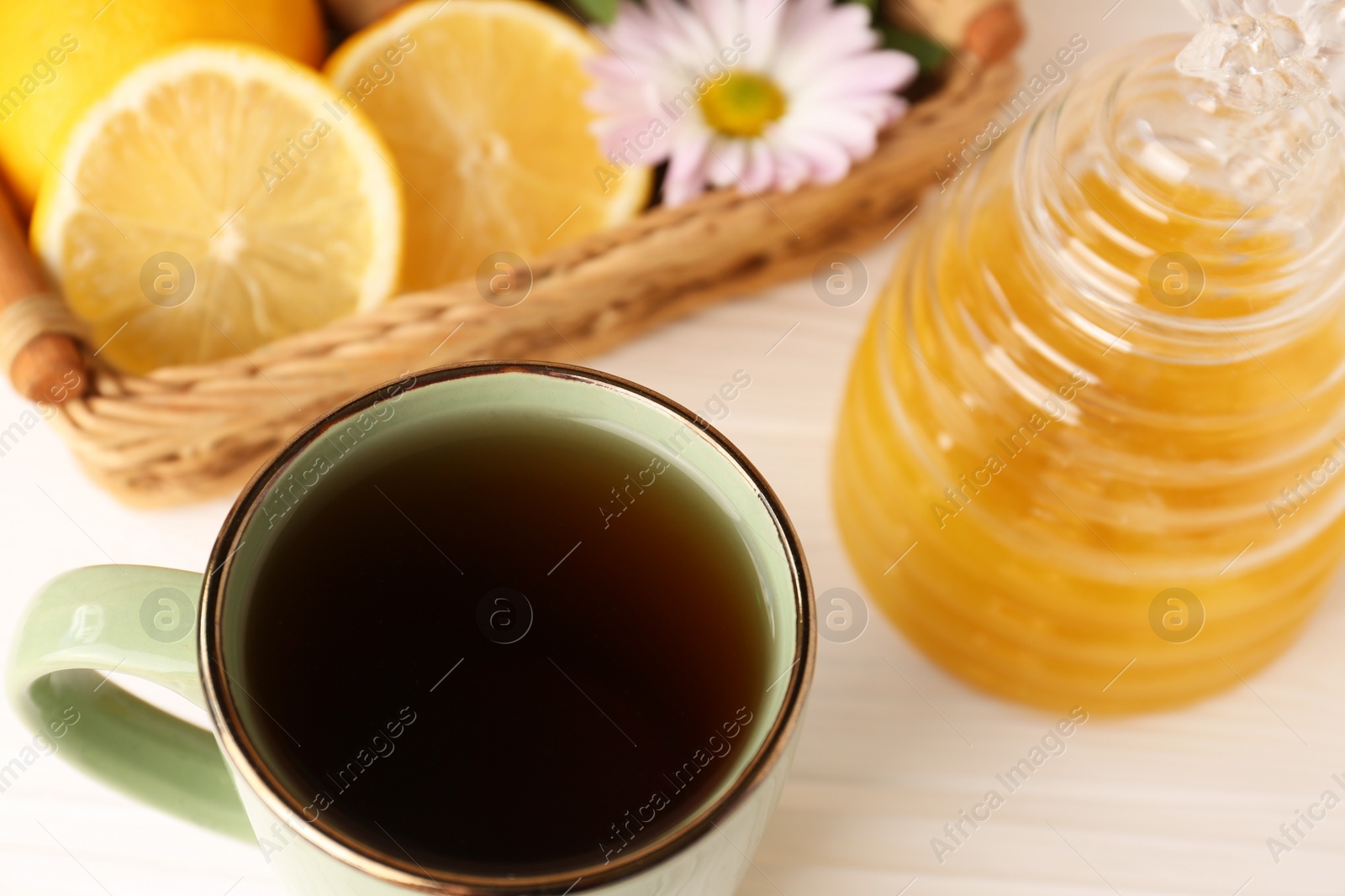 Photo of Mug with delicious tea and honey on white table, closeup