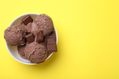 Delicious chocolate ice cream on yellow background, top view. Space for text