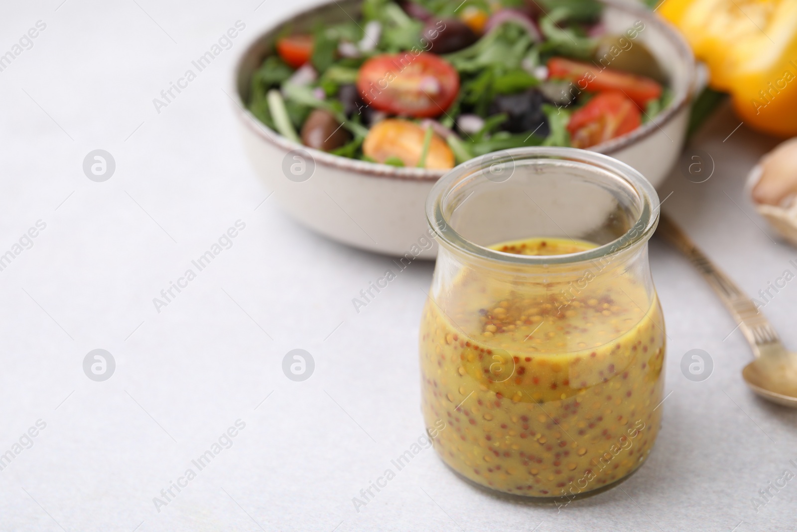 Photo of Tasty vinegar based sauce (Vinaigrette) in jar on light table, closeup. Space for text