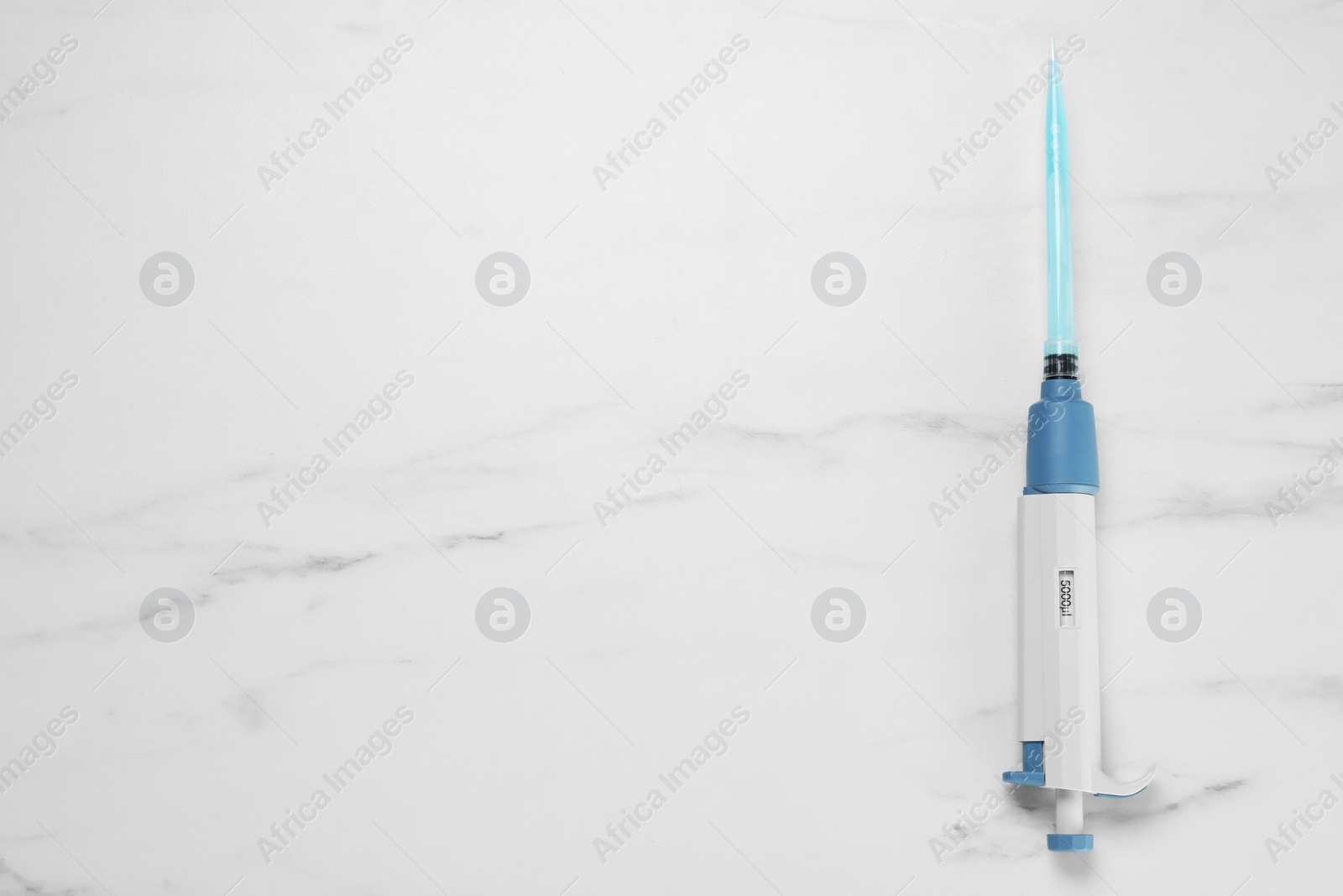 Photo of Laboratory analysis. Micropipette with liquid on white marble table, top view. Space for text