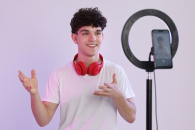 Photo of Smiling teenage blogger explaining something while streaming on white background