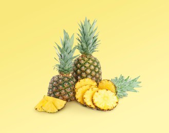 Image of Cut and whole pineapples on light yellow background