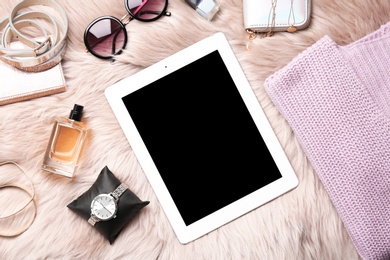 Set of accessories, perfume and tablet computer on faux fur, flat lay. Beauty blogging