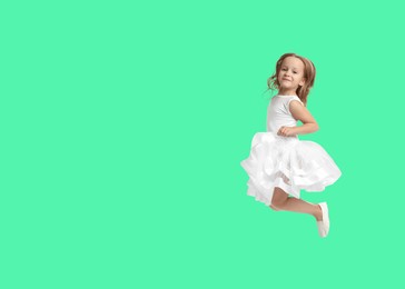 Image of Cute girl jumping on aquamarine background, space for text