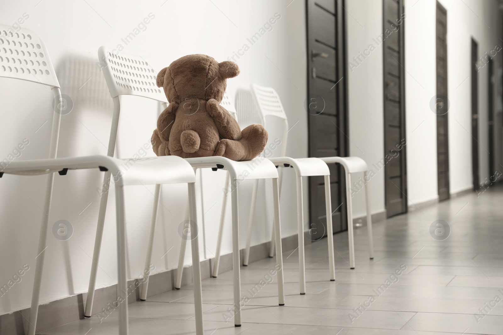 Photo of Cute lonely teddy bear on chair indoors, back view. Space for text